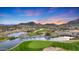 Beautiful aerial view of a meticulously maintained golf course with serene water features and stunning mountain views at 20699 W Ridge Rd, Buckeye, AZ 85396