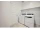 Bright laundry room with full-sized white washer and dryer, plus a built-in shelf for organizing supplies at 25188 N 174Th Ave, Surprise, AZ 85387