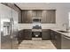 Bright kitchen featuring stainless steel appliances, dark cabinets, quartz countertops, and wood-look tile floors at 3129 S 155Th Ln, Goodyear, AZ 85338