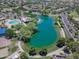 Aerial view of a lake with community recreation area featuring a pool, playground, and open green space with walking trails at 3514 S Posse Trl, Gilbert, AZ 85297