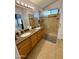 This bathroom includes double sinks with granite countertops, wooden cabinetry, tile flooring, and glass enclosed shower at 3891 E Simpson Rd, Gilbert, AZ 85297