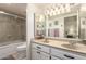 Bathroom featuring a double sink vanity, a large mirror, and a shower/tub combo with glass doors at 400 W Crofton St, Chandler, AZ 85225