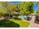 Tranquil backyard with a sparkling pool, artificial grass, and mature trees, creating a private oasis for outdoor enjoyment at 4511 E Kirkland Rd, Phoenix, AZ 85050