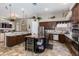 A kitchen with stainless steel appliances, brown cabinets, tile flooring, kitchen island with wine fridge, and dining area at 4511 E Kirkland Rd, Phoenix, AZ 85050