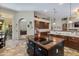Kitchen features brown cabinets, island with glass cooktop, tile flooring, and view into living room at 4511 E Kirkland Rd, Phoenix, AZ 85050