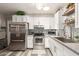 Bright kitchen with stainless steel appliances, white cabinets, decorative shelving, and tiled backsplash at 6802 S 47Th St, Phoenix, AZ 85042