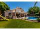 Inviting backyard featuring a pool, covered patio, outdoor kitchen, and lush green lawn, perfect for entertaining at 735 W Kelton Ln, Phoenix, AZ 85023