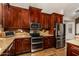 Modern kitchen design with stainless steel appliances, cherry cabinets, and granite countertops at 735 W Kelton Ln, Phoenix, AZ 85023