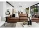 Modern living room with vaulted ceiling, black beams, leather sofa, and expansive sliding glass doors at 7774 E San Fernando Dr, Scottsdale, AZ 85255
