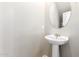 A sleek pedestal sink and round mirror in a half bathroom with neutral paint at 778 W Lowell Dr, San Tan Valley, AZ 85140