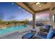 Inviting covered patio with ceiling fan and wicker furniture overlooks pool with stone waterfall feature at 778 W Lowell Dr, San Tan Valley, AZ 85140