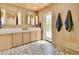 Well-lit bathroom with double sink vanity, mosaic tile flooring, and door leading to the outdoors at 1712 E Fairfield St, Mesa, AZ 85203