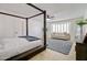 Spacious bedroom featuring a stylish four-poster bed, ceiling fan, and bay window with a cozy sitting area at 1712 E Fairfield St, Mesa, AZ 85203