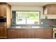 Modern kitchen with wood cabinetry, stone countertop, and backyard access at 1712 E Fairfield St, Mesa, AZ 85203