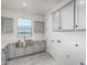 Well-lit laundry room features gray cabinets and stainless steel sink at 17322 W Puget Ave, Waddell, AZ 85355