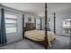 Main bedroom with dark wood canopy bed, neutral bedding, and large windows at 1799 N 209Th Ave, Buckeye, AZ 85396