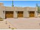 Three-car garage showcasing paneled wooden doors and unique sconce lighting, set against a desert landscape at 2304 Fox Tail Trl, Carefree, AZ 85377