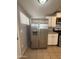 A stainless steel refrigerator stands adjacent to the kitchen counter and white cabinets with tiled flooring at 2745 E Wood St, Phoenix, AZ 85040
