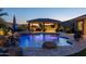 A nighttime view of the pool with a unique shape, a rock waterfall, and an outdoor kitchen at 3119 E Bellflower Dr, Gilbert, AZ 85298