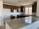 Bright kitchen featuring granite counters, dark wood cabinets, stainless steel sink and a large window at 32016 N Pony Express Rd, San Tan Valley, AZ 85143
