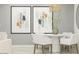 Stylish dining area with modern art, a round table, and white chairs under a woven pendant light at 36550 W Maddaloni Ave, Maricopa, AZ 85138
