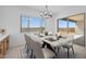 Elegant dining room with a marble table, white chairs, modern chandelier, and a sliding glass door at 37695 W Santa Maria St, Maricopa, AZ 85138