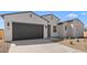 Stunning view of a one-story home with a dark garage door and desert landscaping at 37695 W Santa Maria St, Maricopa, AZ 85138