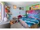 bedroom is decorated with stuffed animals, posters, colorful bedspread, and carpet floors at 3871 W Linda Ln, Chandler, AZ 85226