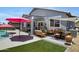 Beautiful patio area with stylish furnishings, artificial turf, and a sparkling pool with a bright pink umbrella at 4231 E Augusta Ave, Chandler, AZ 85249