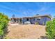 Large backyard featuring a brick home, covered patio, stone wall, green shrubbery, and dead grass at 4363 E Dragoon Cir, Mesa, AZ 85206