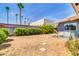 Backyard featuring a stone wall, shrubbery, dead grass, palm trees, and a partial view of the home at 4363 E Dragoon Cir, Mesa, AZ 85206