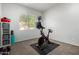 Compact exercise room equipped with a stationary bike, shelving, and a padded floor area at 4618 W Pokeberry Ln, Phoenix, AZ 85083