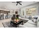 Open-concept living room with gray sectional couch, ceiling fan and views of the kitchen and outdoor patio at 4618 W Pokeberry Ln, Phoenix, AZ 85083