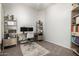 Well-lit home office with an adjustable desk, dual monitors, wooden shelves, and a comfortable chair at 4618 W Pokeberry Ln, Phoenix, AZ 85083