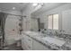 Bathroom showcasing a dual-sink granite vanity, large mirror, and a shower-tub combo at 7930 W Colter St, Glendale, AZ 85303