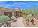 Charming home entrance with a brick walkway, desert landscaping, and an arched wooden door at 8154 E Tecolote Cir, Scottsdale, AZ 85266