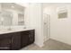 Well-lit bathroom with dual sinks, dark cabinets, and walk-in shower at 8634 W Albeniz Pl, Tolleson, AZ 85353
