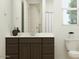 Bright bathroom with a large mirror, white counter, dark cabinets, and a white toilet at 9522 W Avalon Dr, Phoenix, AZ 85037
