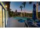 Inviting backyard oasis featuring a sparkling pool, spa, lighted palm trees, and mountain views at dusk at 15411 S 13Th Ave, Phoenix, AZ 85045