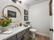 Charming powder room with an elegant round mirror, gray vanity and wood-look floors at 15411 S 13Th Ave, Phoenix, AZ 85045