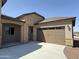 View of the home's stone-accented facade, three car garage, and covered entry at 17308 W Royal Palm Rd, Waddell, AZ 85355