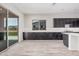 Bright, open-concept kitchen area with dark cabinets, light countertops and a large sliding glass door at 17308 W Royal Palm Rd, Waddell, AZ 85355