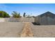 Rock landscaping in the backyard with access to the storage shed and white block privacy fence at 2036 W Windrose Dr, Phoenix, AZ 85029