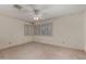 A carpeted bedroom with a ceiling fan and a view of a window with shutters at 2050 W Nido Ave, Mesa, AZ 85202