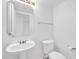 Powder room featuring a pedestal sink, decorative mirror, and toilet at 22019 N 59Th Dr, Glendale, AZ 85310