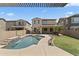 This backyard features a refreshing pool, lush lawn, patio, and a beige two-story home at 2213 N Park Meadows Dr, Buckeye, AZ 85396