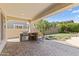 Outdoor kitchen with a stone counter, a grill, and bar stool seating in the covered patio at 2213 N Park Meadows Dr, Buckeye, AZ 85396