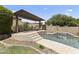 Tranquil pool area with a shaded lounge area, a waterfall feature, and lush landscaping at 2213 N Park Meadows Dr, Buckeye, AZ 85396