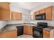 Functional kitchen with wood cabinets, black appliances, a dual basin sink, and tile flooring at 2311 E Hartford Ave # 29, Phoenix, AZ 85022