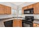 Functional kitchen with wood cabinets and black appliances, offering practical layout at 2311 E Hartford Ave # 29, Phoenix, AZ 85022